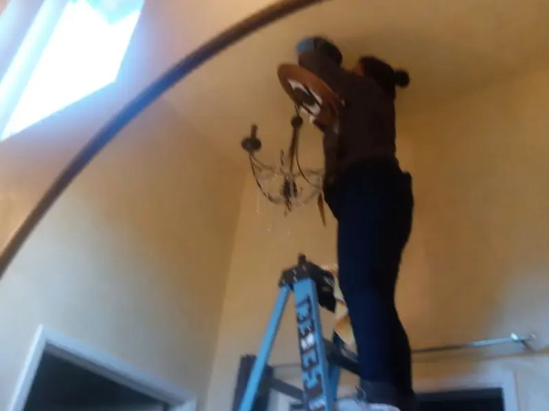 Electrician installing a chandelier in a Lucas residence